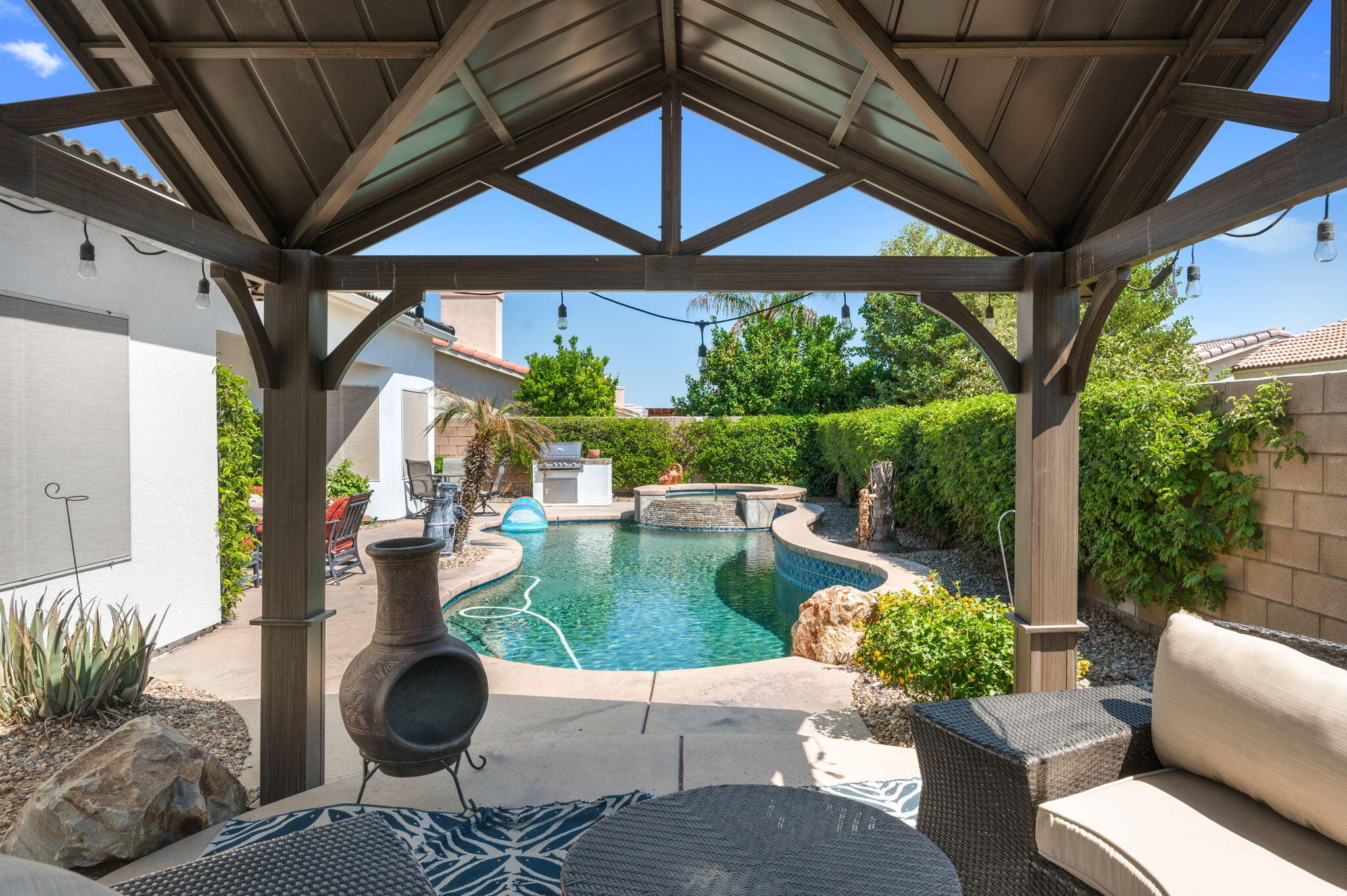 83035 Exeter Court Thermal, CA 92274 - Photo 35 of 38 a view of a patio with couches table and chairs under an umbrella with a fire pit
