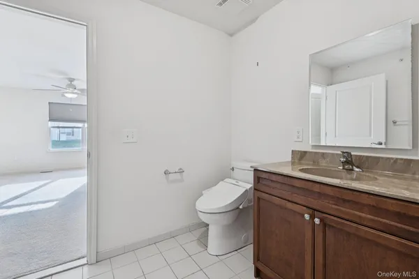 a bathroom with a granite countertop sink a toilet and a mirror