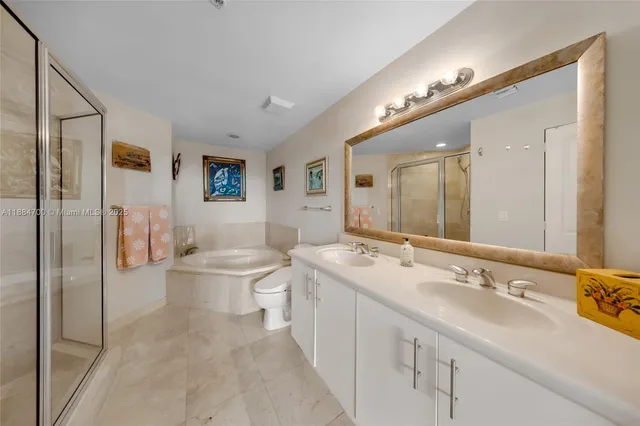 a spacious bathroom with a double vanity sink toilet mirror and bathtub