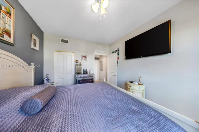 a spacious bedroom with a bed and a flat screen tv