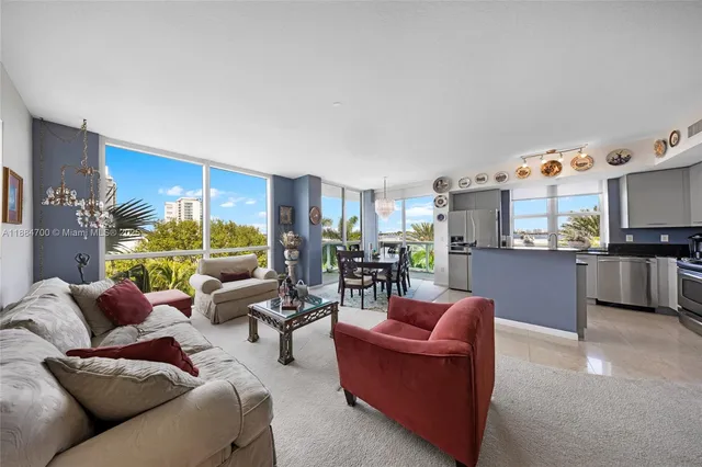 a living room with furniture kitchen view and a large window