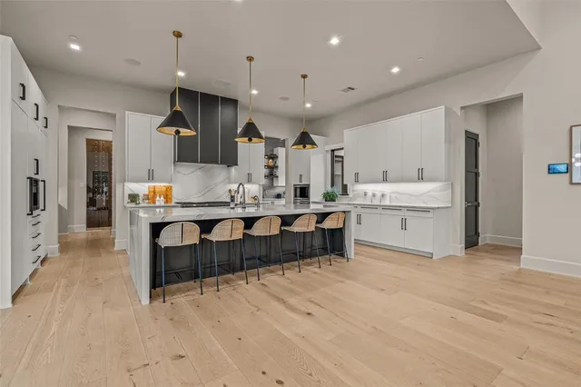 a large kitchen with cabinets chairs and wooden floor