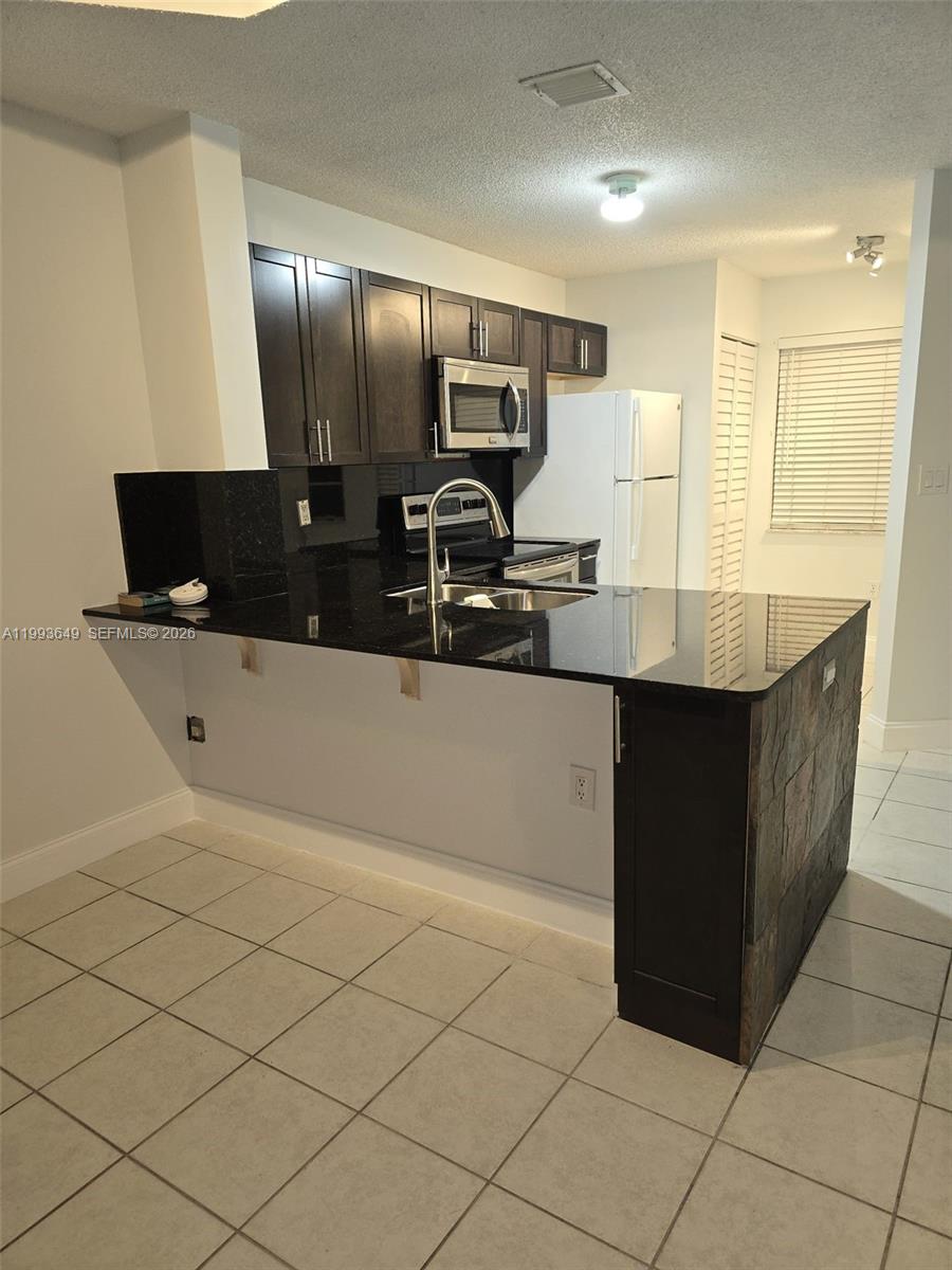 14272 Southwest 121st Place, Unit 9 Miami, FL 33186 - Photo 6 of 17 a kitchen with stainless steel appliances a sink and a refrigerator