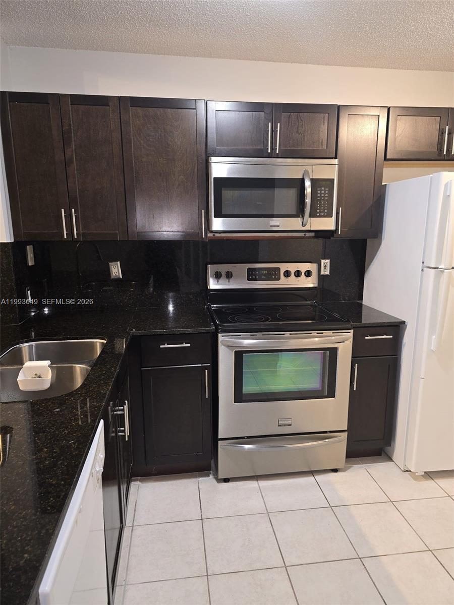 14272 Southwest 121st Place, Unit 9 Miami, FL 33186 - Photo 9 of 17 a kitchen with granite countertop a stove and a refrigerator