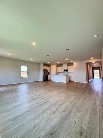 a view of empty room with wooden floor and window