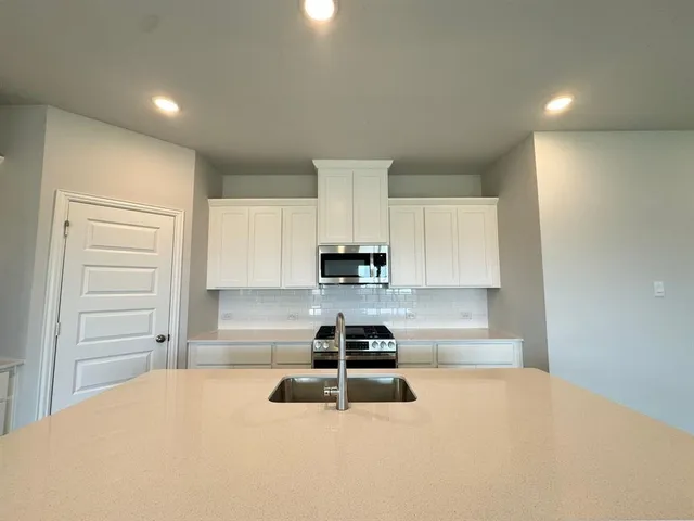 a large white kitchen with kitchen island a stove a sink a refrigerator and a stove