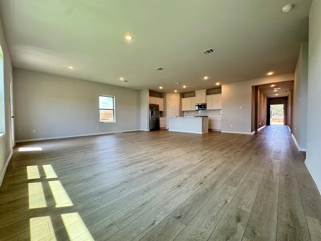 a view of a big room with wooden floor and windows