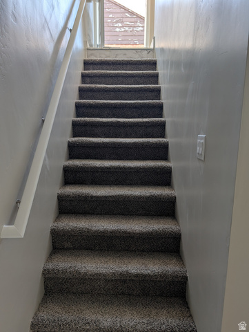 2880 Merton Way Magna, UT 84044 - Photo 21 of 30 Carpeted staircase with a white handrail, light gray wall finish, and a window at the landing