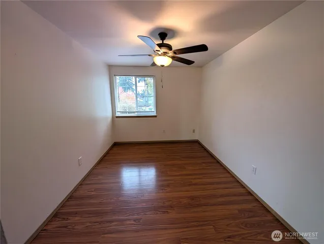 a view of empty room with wooden floor and fan