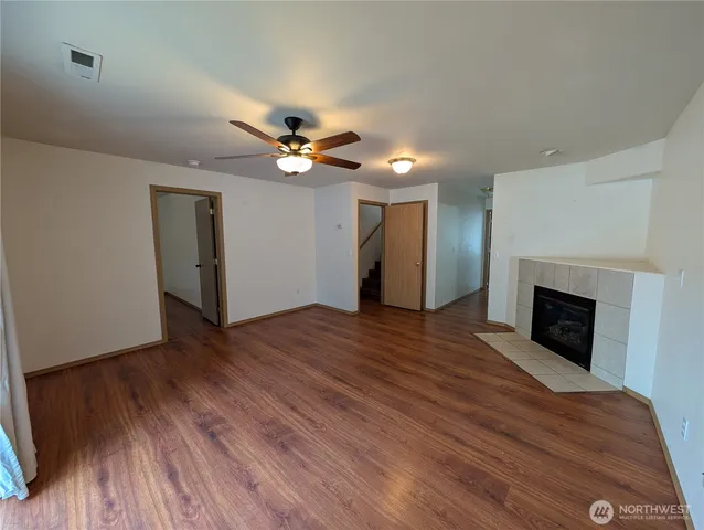 a view of an empty room with wooden floor and a fireplace
