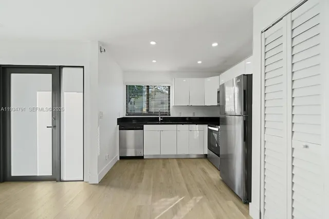 a kitchen with granite countertop stainless steel appliances a refrigerator a sink and cabinets