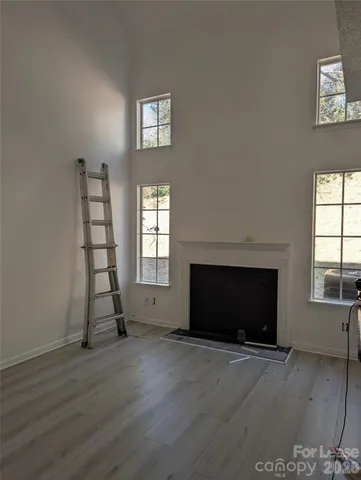 an empty room with wooden floor a fireplace and windows