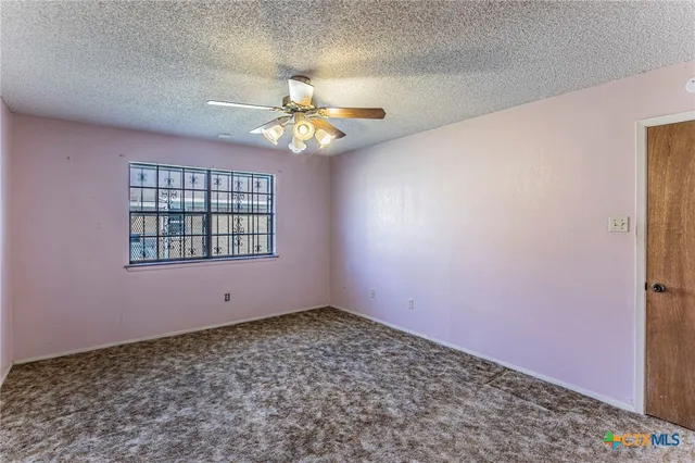 en empty room with windows and ceiling fan