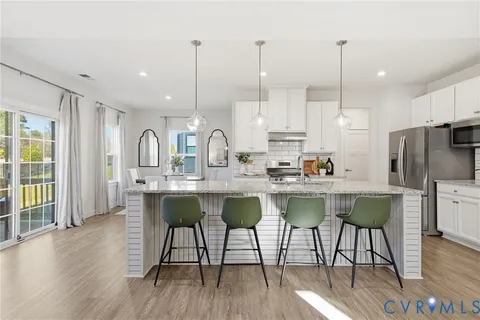 a kitchen with stainless steel appliances granite countertop a stove a refrigerator a oven a sink with island chairs and wooden floor