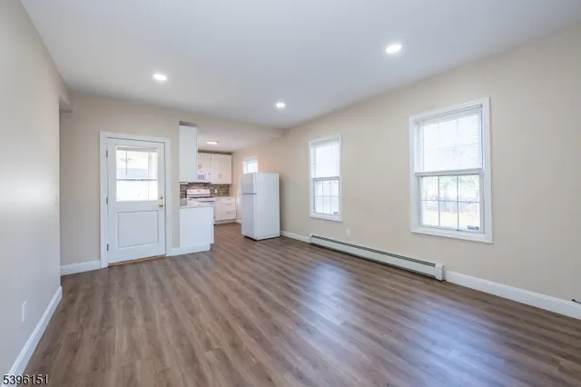 a view of an empty room with window and wooden floor