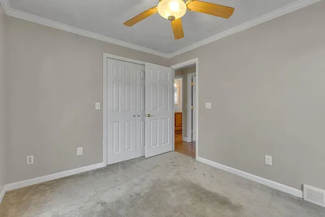 a view of an empty room and chandelier fan