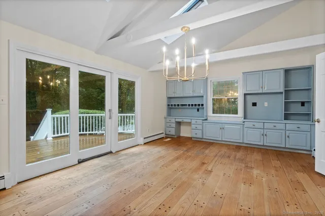 a view of an empty room with wooden floor and a kitchen