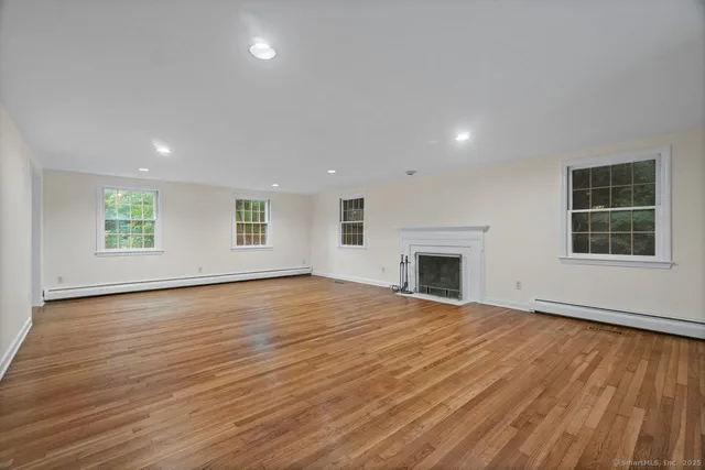 a view of empty room with wooden floor and fireplace