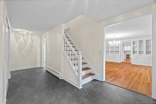 a view of an empty room with wooden floor and stairs
