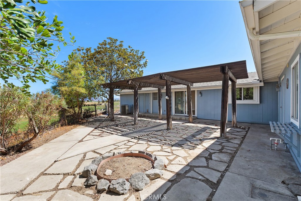 34881 Los Nogales Road Temecula, CA 92592 - Photo 15 of 50 Back of the home with wooden covered patio and concrete inlay and a fire pit. There are also views to the west.