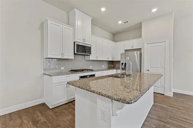 a kitchen with kitchen island granite countertop a stove sink and microwave