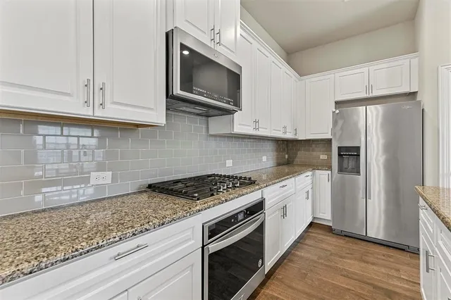a kitchen with stainless steel appliances granite countertop a stove a refrigerator and a microwave