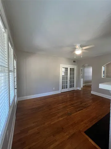 a view of an empty room with wooden floor and a window