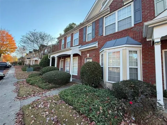 a view of a brick house with a yard and large trees