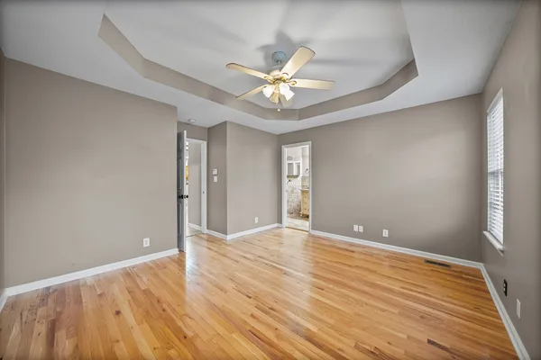 a view of an empty room with window and wooden floor