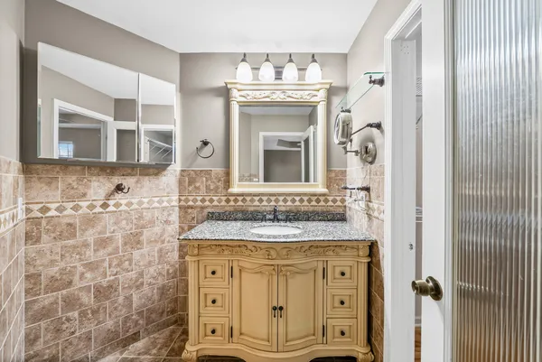 a bathroom with a granite countertop sink a mirror and a shower