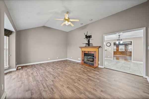 an empty room with windows fireplace and fans