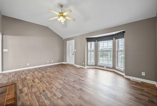 a view of an empty room with window and wooden floor