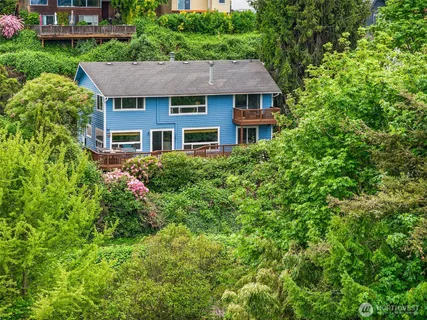 a aerial view of a house with yard and trees in the background
