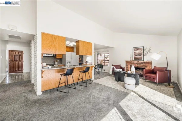 a living room with furniture a rug and kitchen view