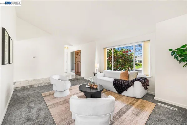 a living room with furniture a large window and dresser
