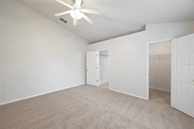 an empty room with closet and a ceiling fan