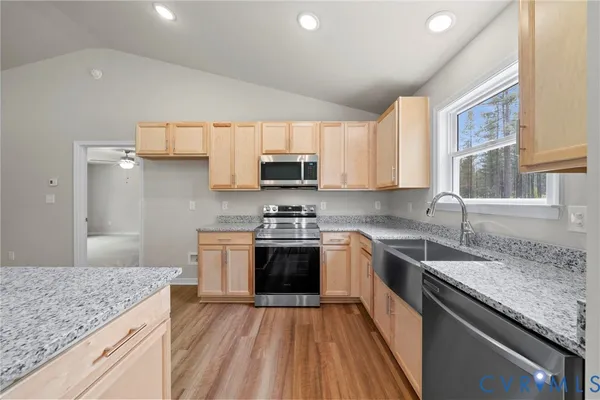 a kitchen with stainless steel appliances granite countertop a stove a sink and a microwave