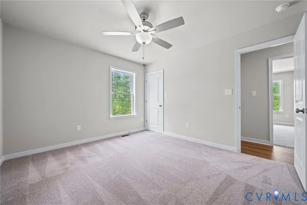 an empty room with a chandelier fan and windows