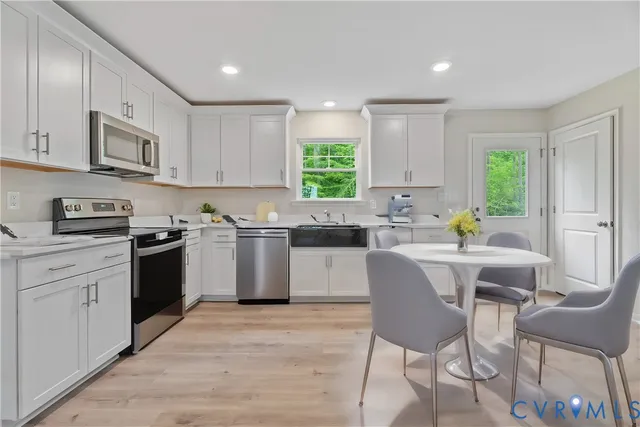 a kitchen with a stove a sink a microwave a dining table and chairs