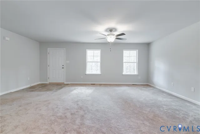 an empty room with windows and chandelier fan