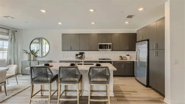 a kitchen with stainless steel appliances a dining table chairs refrigerator and sink