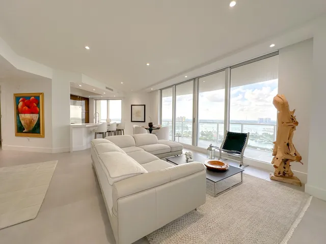 a living room with furniture floor to ceiling window and a flat screen tv