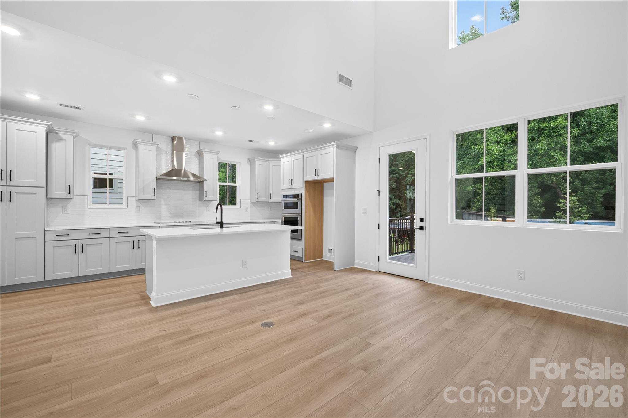 416 Celestial Drive Tega Cay, SC 29708 - Photo 7 of 21 a large white kitchen with kitchen island a stove a sink a refrigerator and white cabinets with wooden floor