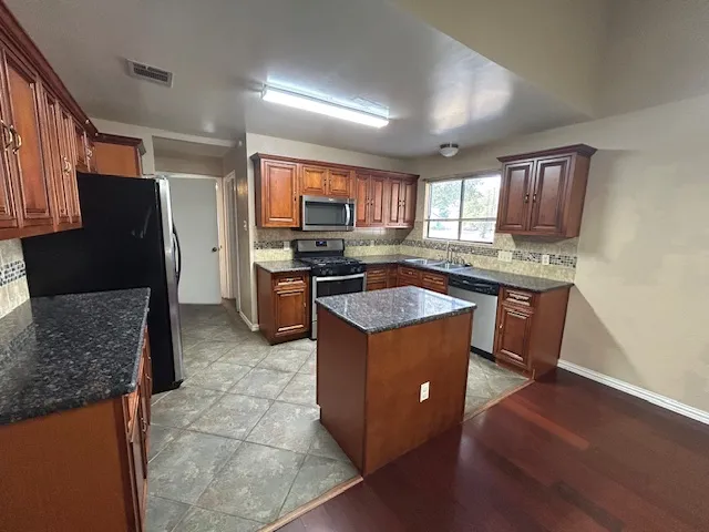 a kitchen with stainless steel appliances granite countertop a sink stove and refrigerator