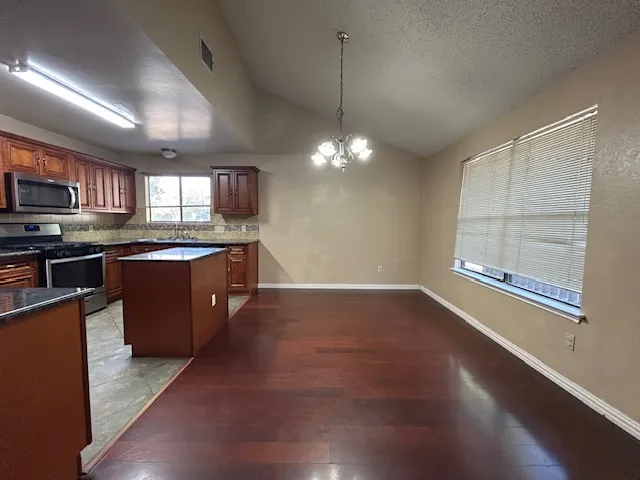 a kitchen with stainless steel appliances granite countertop a stove a sink and a microwave