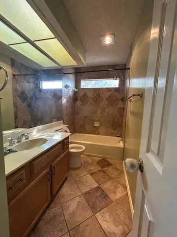 a bathroom with a granite countertop sink a toilet and shower