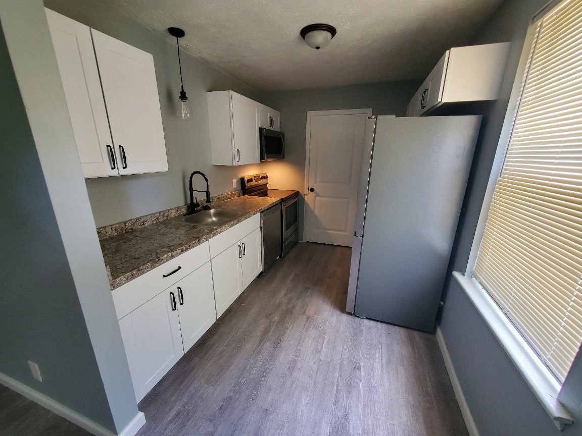 1317 Pierce Road Madison, TN 37115 - Photo 5 of 18 a kitchen with granite countertop a refrigerator a sink and wooden floor