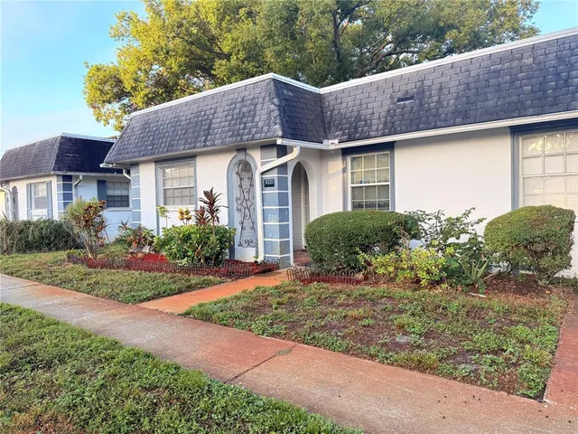 a front view of a house with a yard and potted plants