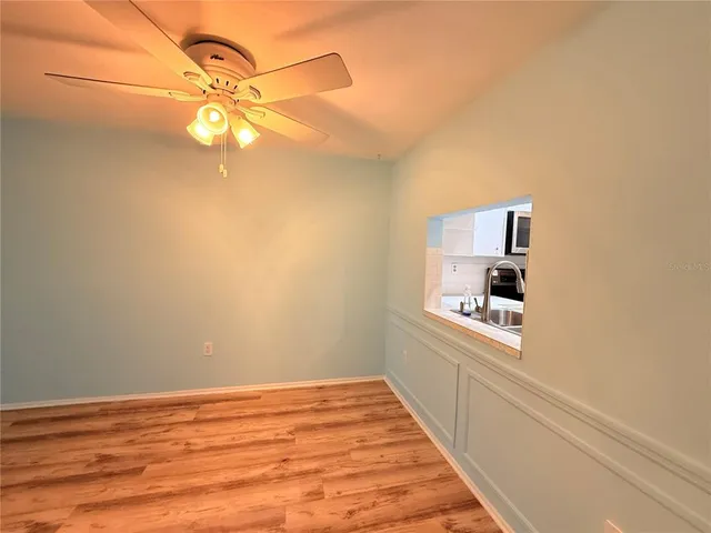 a view of a room with a hanging light and hardwood floor
