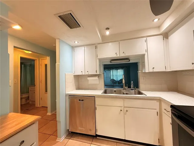 a kitchen with kitchen island granite countertop a sink cabinets and stainless steel appliances